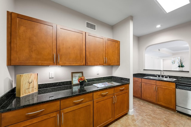 kitchen with visible vents, a sink, dark stone countertops, brown cabinetry, and dishwasher