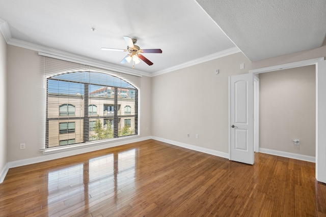 unfurnished room featuring baseboards, wood finished floors, a ceiling fan, and crown molding