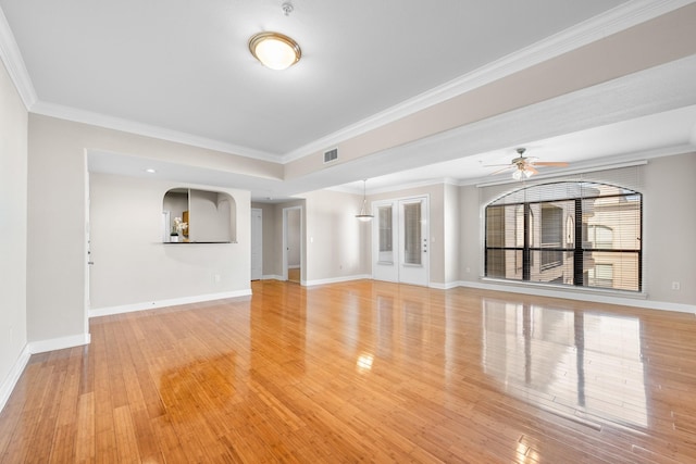 unfurnished living room with light wood-type flooring, visible vents, ornamental molding, a ceiling fan, and baseboards