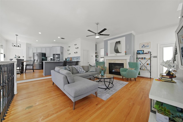 living room featuring light wood-type flooring, a fireplace, and crown molding