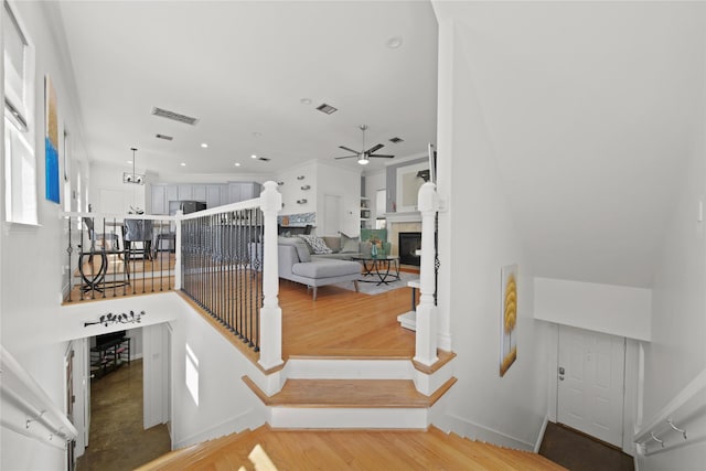 staircase with visible vents, a ceiling fan, wood finished floors, and a fireplace