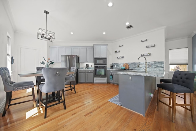 kitchen with black oven, built in microwave, a breakfast bar area, gray cabinets, and a sink