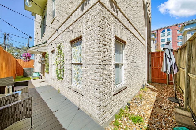 view of property exterior with brick siding, a deck, and a fenced backyard