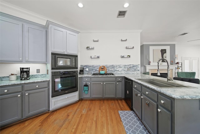 kitchen with gray cabinets, black appliances, and a sink