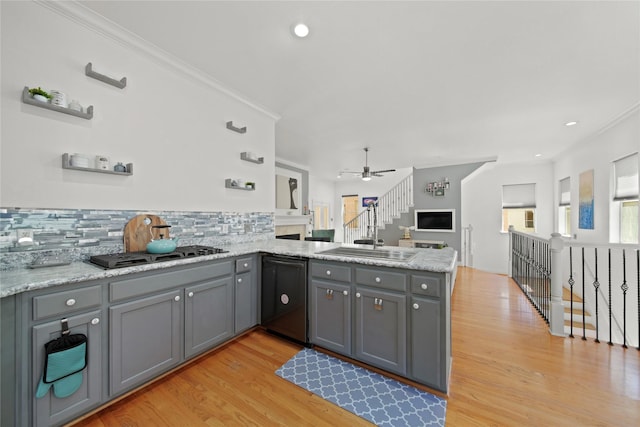 kitchen with a peninsula, gray cabinets, a sink, stainless steel gas stovetop, and dishwasher