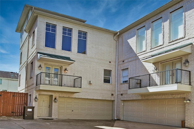 rear view of house with a garage, brick siding, and fence