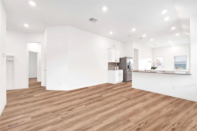 unfurnished living room featuring visible vents, recessed lighting, light wood-type flooring, and baseboards