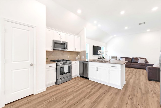 kitchen featuring visible vents, open floor plan, stainless steel appliances, a peninsula, and vaulted ceiling