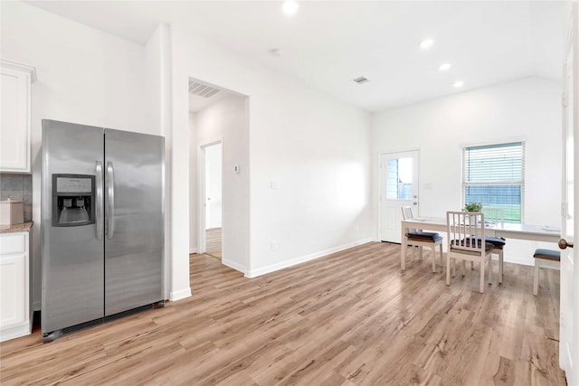 kitchen with visible vents, stainless steel fridge, white cabinets, and light wood finished floors