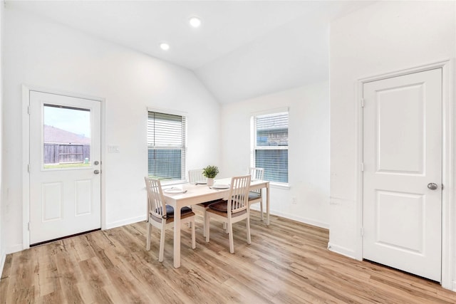 dining area featuring light wood-style flooring, baseboards, and lofted ceiling