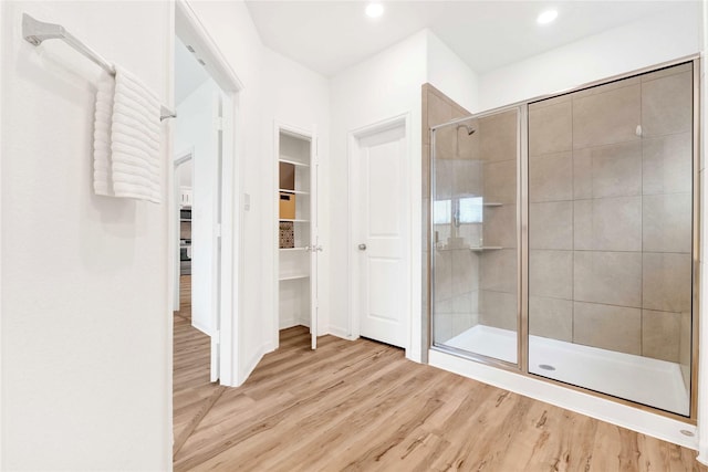 full bathroom featuring a walk in closet, recessed lighting, wood finished floors, and a stall shower