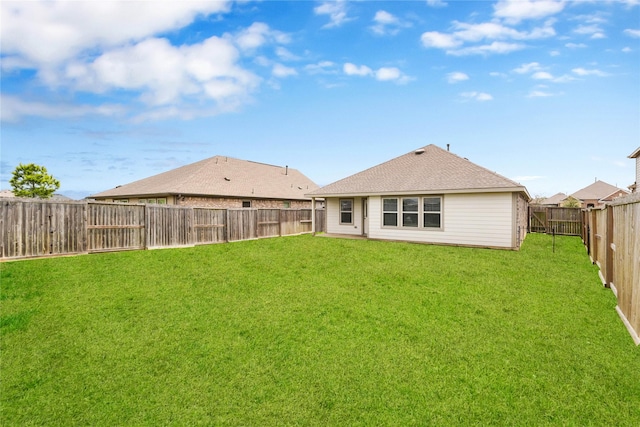 rear view of house with a lawn, a fenced backyard, and roof with shingles