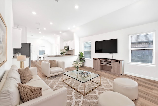 living area featuring a wealth of natural light, lofted ceiling, and light wood-style flooring