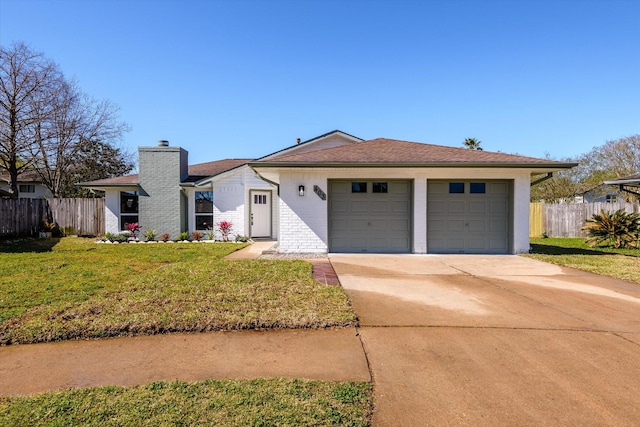 view of front of home with a front yard, fence, driveway, an attached garage, and a chimney