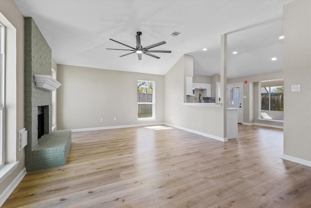 unfurnished living room with visible vents, ceiling fan, light wood-type flooring, vaulted ceiling, and a fireplace