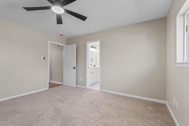 unfurnished bedroom featuring ensuite bathroom, baseboards, carpet floors, and ceiling fan