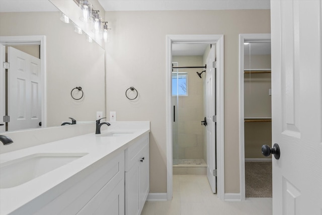 bathroom featuring a shower stall, a spacious closet, double vanity, and a sink