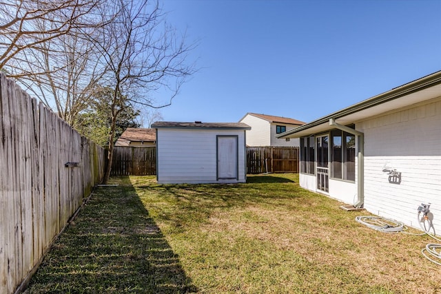 view of yard with a shed, an outdoor structure, a fenced backyard, and a sunroom