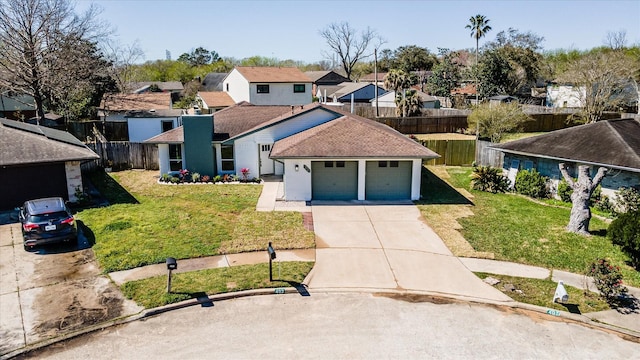 view of front of property featuring a front yard, fence, driveway, an attached garage, and a residential view