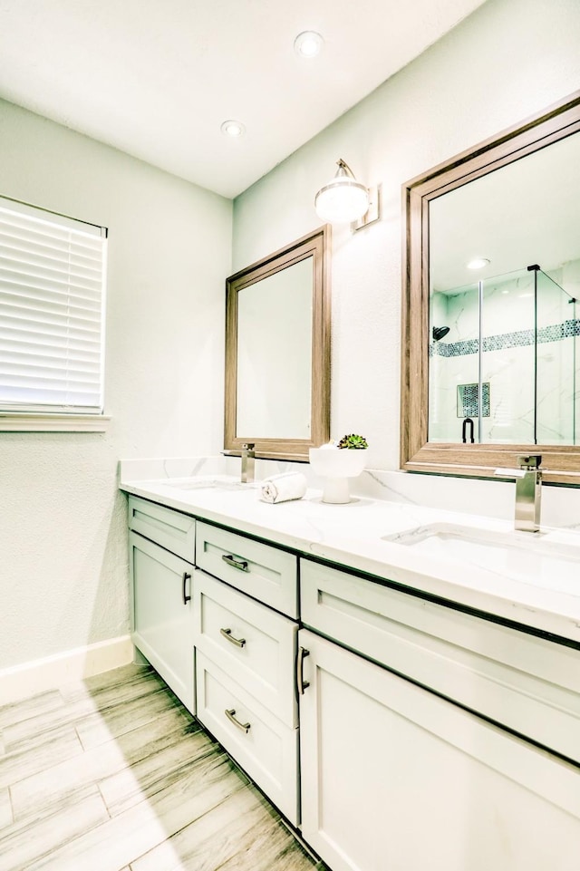 bathroom with double vanity, a stall shower, and a sink