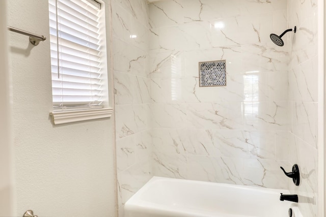 bathroom with shower / washtub combination and a textured wall