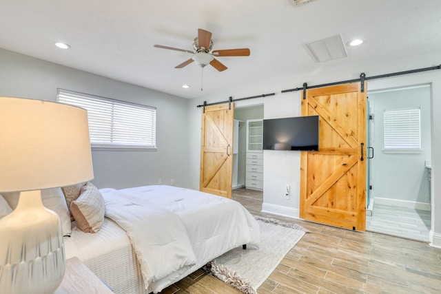 bedroom featuring a barn door, recessed lighting, baseboards, and light wood finished floors