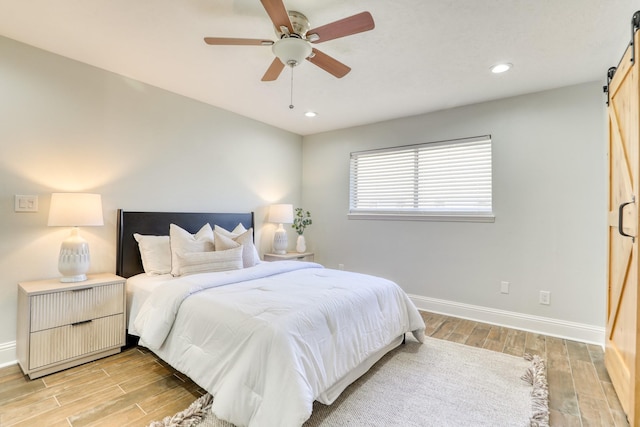 bedroom featuring recessed lighting, baseboards, light wood-style floors, and a barn door