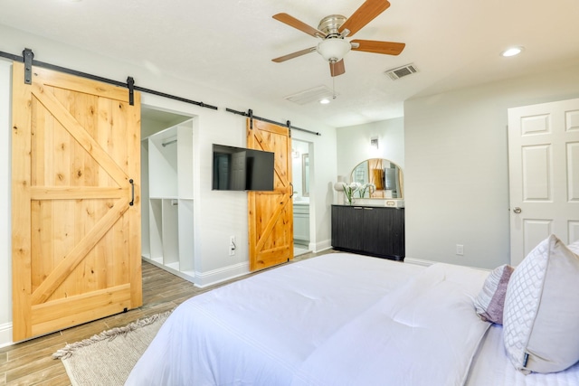 bedroom featuring visible vents, wood finished floors, recessed lighting, a barn door, and baseboards