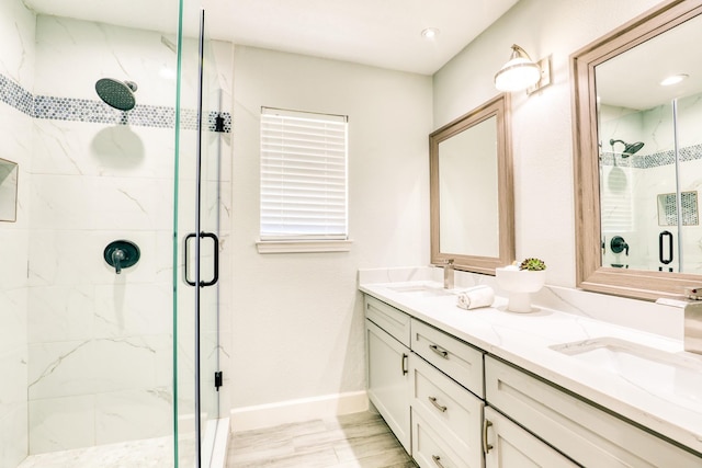 bathroom with double vanity, baseboards, a marble finish shower, and a sink