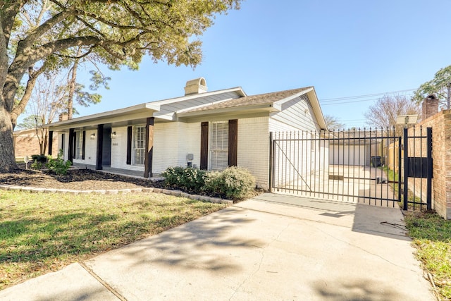 ranch-style house with brick siding, fence, a chimney, driveway, and a gate