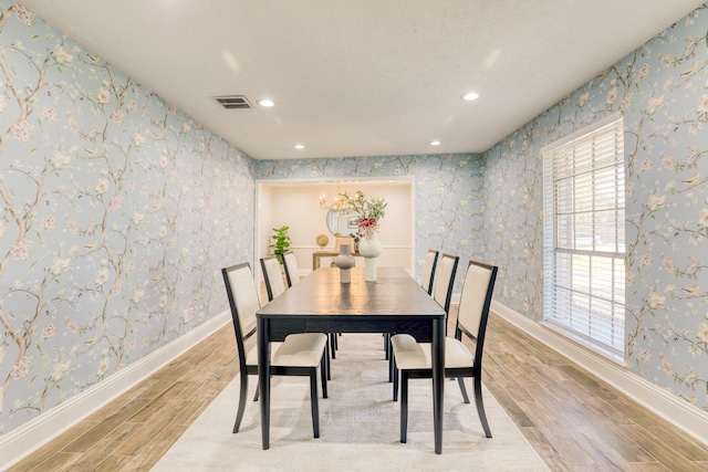 dining room with wood finish floors, visible vents, baseboards, and wallpapered walls