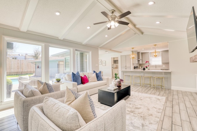 living room featuring a ceiling fan, baseboards, wood tiled floor, vaulted ceiling with beams, and a textured ceiling