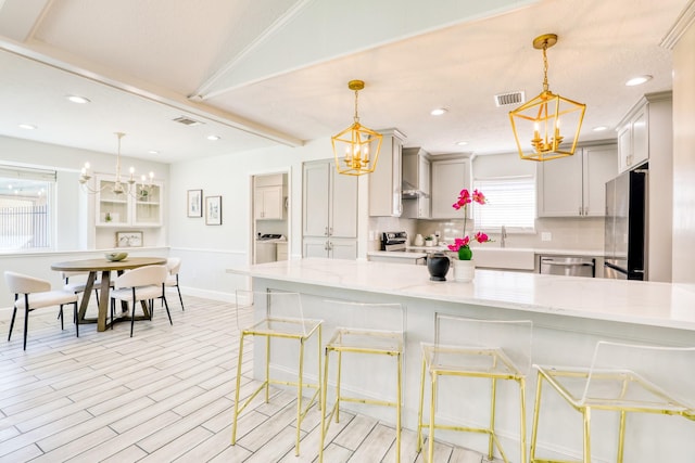 kitchen with light stone countertops, tasteful backsplash, appliances with stainless steel finishes, and a chandelier