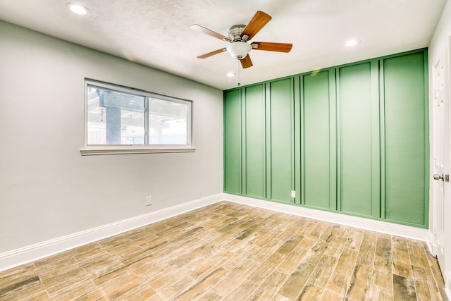 spare room with recessed lighting, light wood-style flooring, a ceiling fan, and baseboards