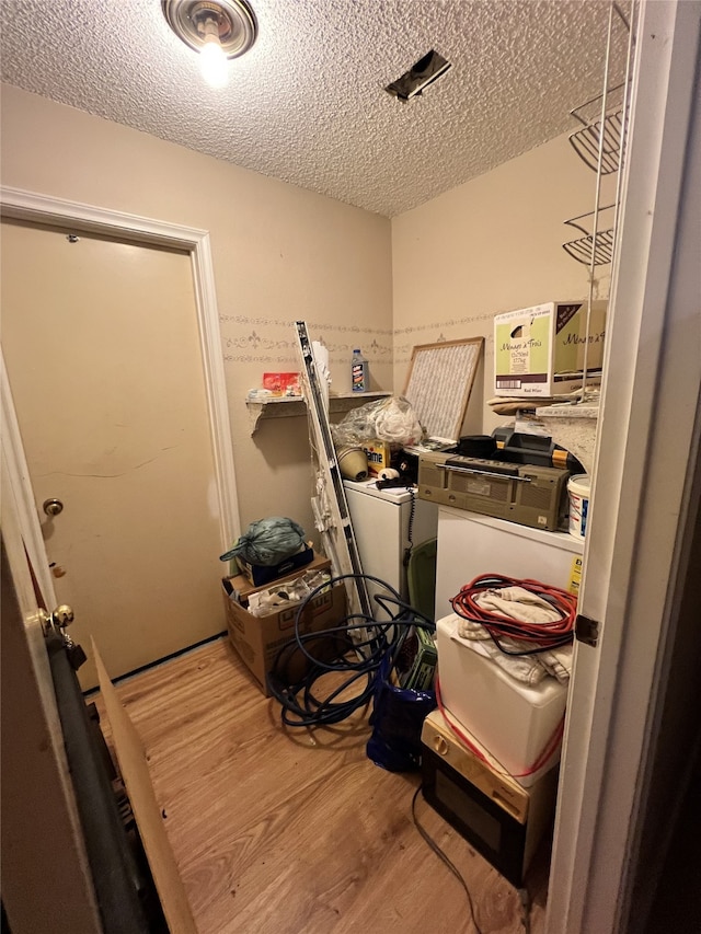 clothes washing area featuring laundry area, independent washer and dryer, a textured ceiling, and wood finished floors