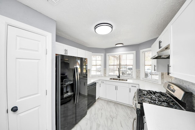 kitchen featuring marble finish floor, black appliances, under cabinet range hood, a sink, and white cabinets