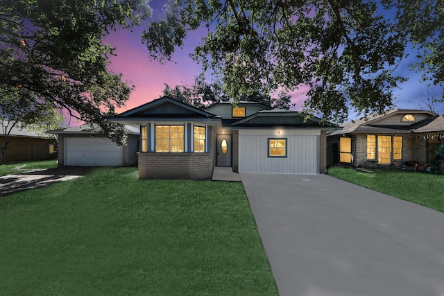 view of front of property featuring a yard, brick siding, and concrete driveway