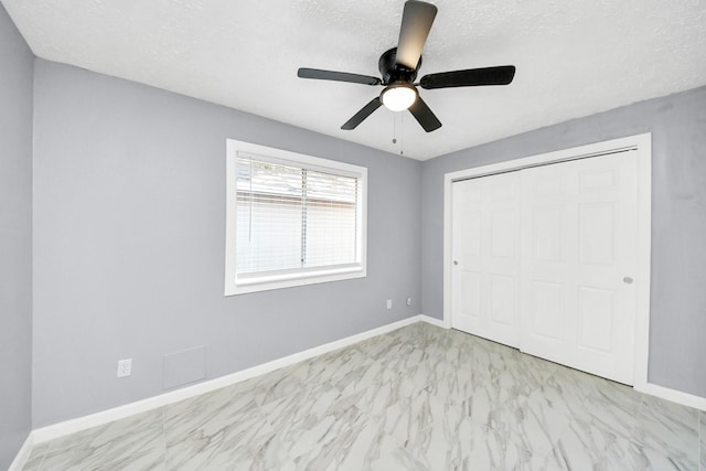 unfurnished bedroom featuring a closet, baseboards, a textured ceiling, and marble finish floor