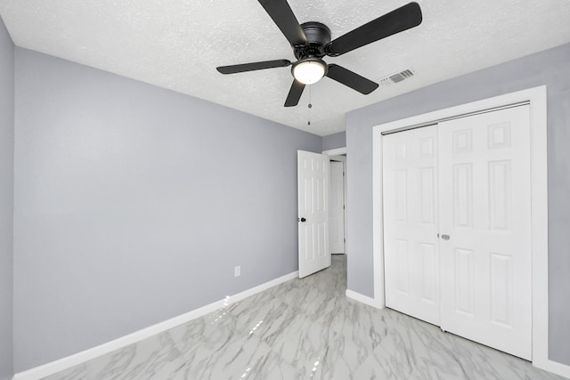 unfurnished bedroom with visible vents, baseboards, a closet, marble finish floor, and a textured ceiling