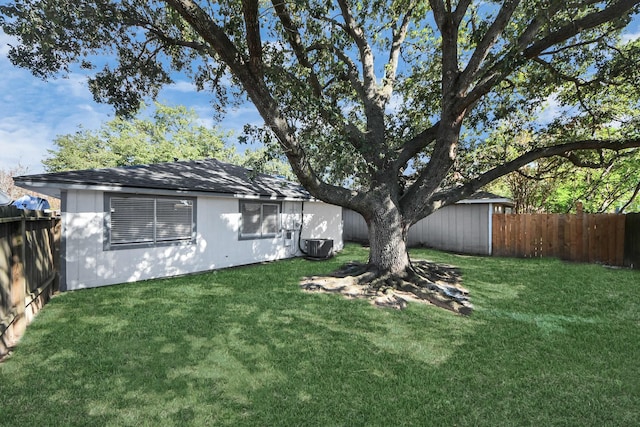 view of yard featuring an outbuilding, cooling unit, a storage unit, and a fenced backyard