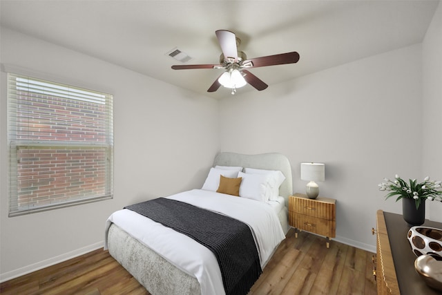 bedroom with wood finished floors, visible vents, and baseboards