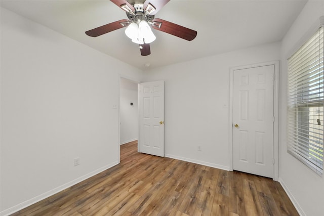 unfurnished bedroom with a ceiling fan, wood finished floors, and baseboards