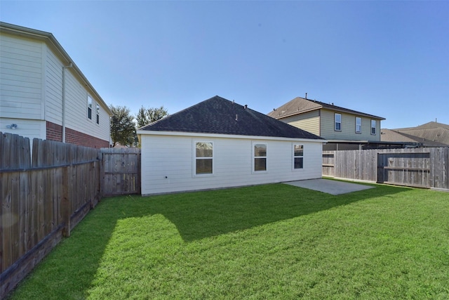 back of property featuring a fenced backyard, a patio area, a yard, and roof with shingles