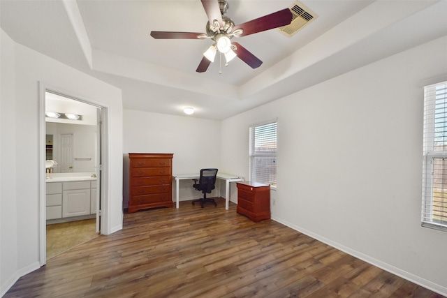 office area featuring visible vents, a raised ceiling, baseboards, and wood finished floors