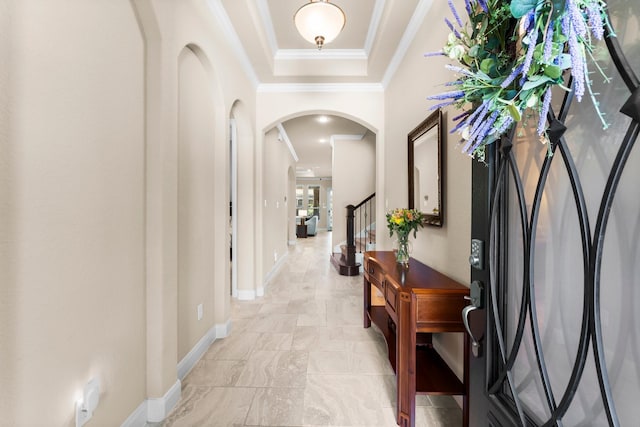 entrance foyer with crown molding, baseboards, stairs, arched walkways, and a raised ceiling