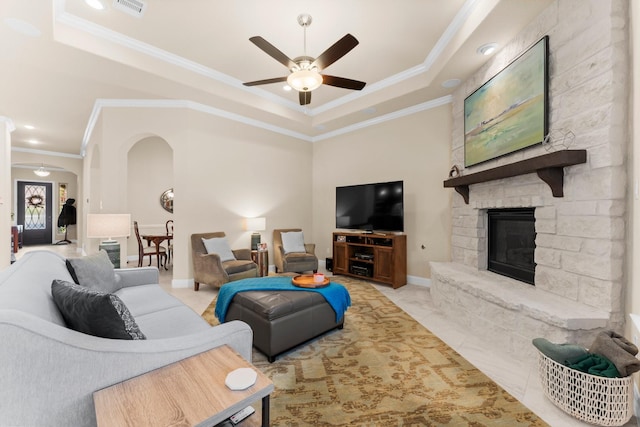 living room featuring a tray ceiling, visible vents, arched walkways, and ceiling fan