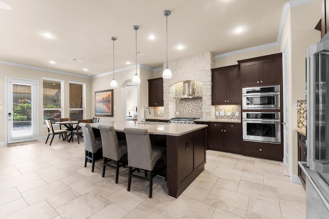 kitchen with stainless steel appliances, tasteful backsplash, dark brown cabinets, and wall chimney range hood