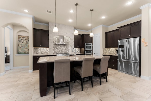 kitchen with visible vents, an island with sink, stainless steel appliances, wall chimney exhaust hood, and dark brown cabinets