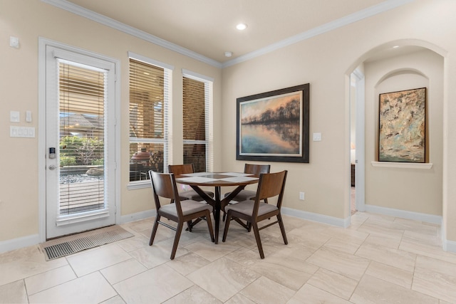 dining space featuring arched walkways, recessed lighting, crown molding, and baseboards