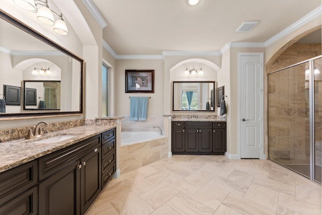 full bath with a shower stall, a garden tub, two vanities, ornamental molding, and a sink